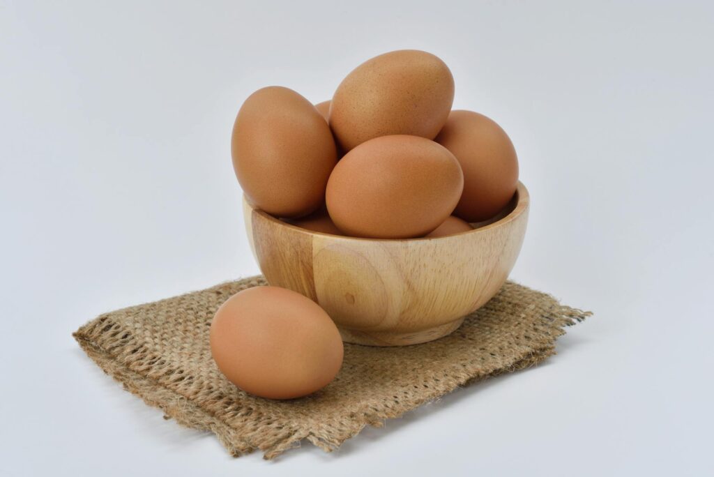 brown eggs on brown wooden bowl on beige knit textile