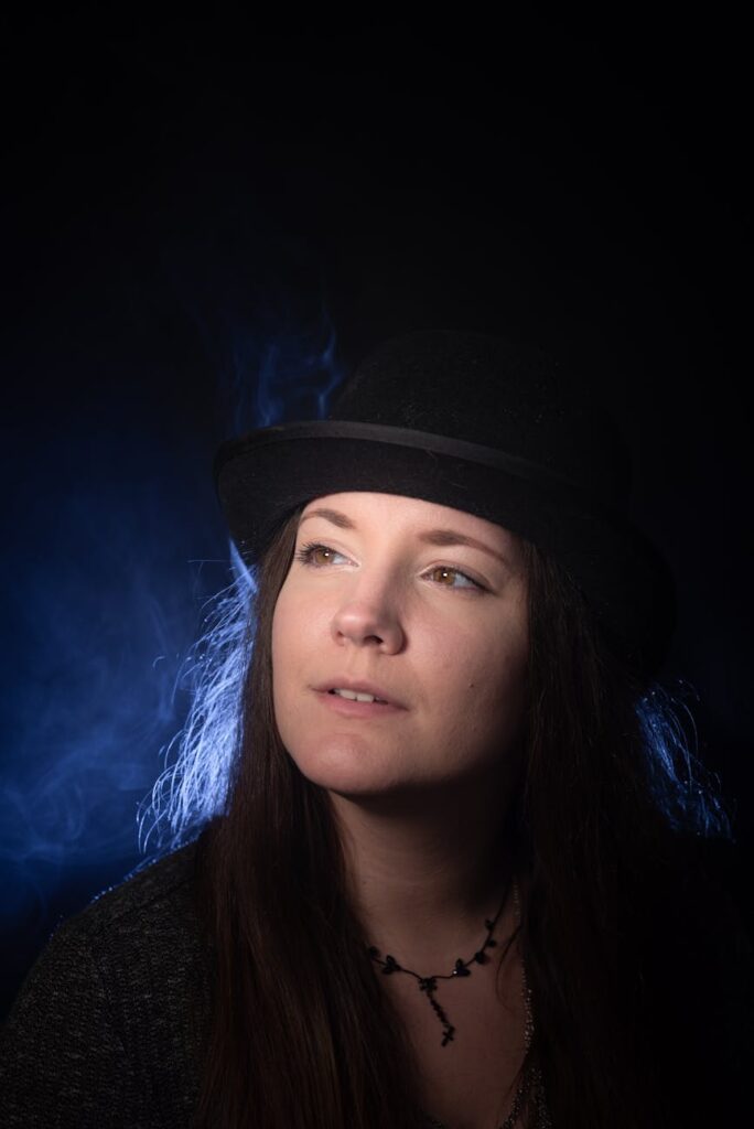 portrait of a woman wearing a black cylinder hat against night sky