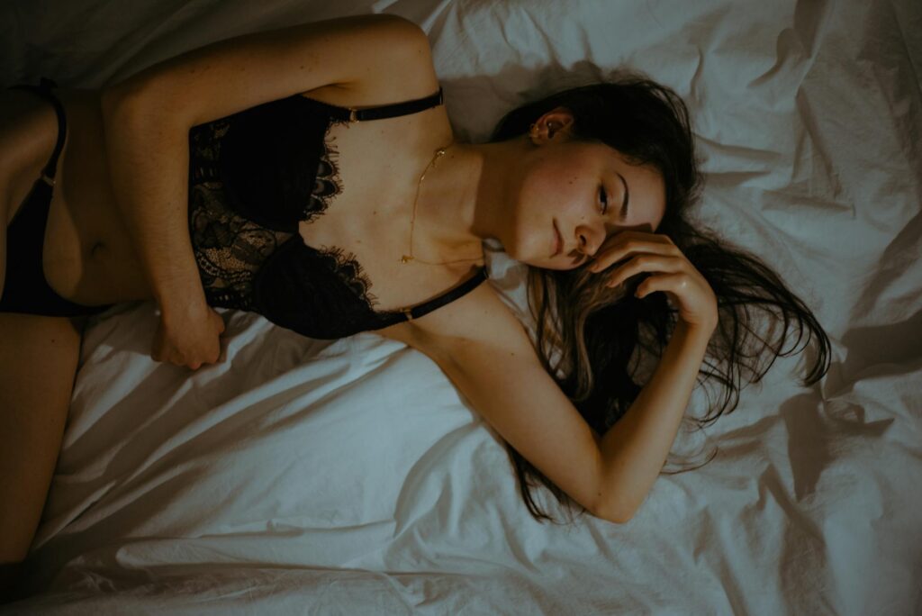 woman wearing black lingerie lying on bed