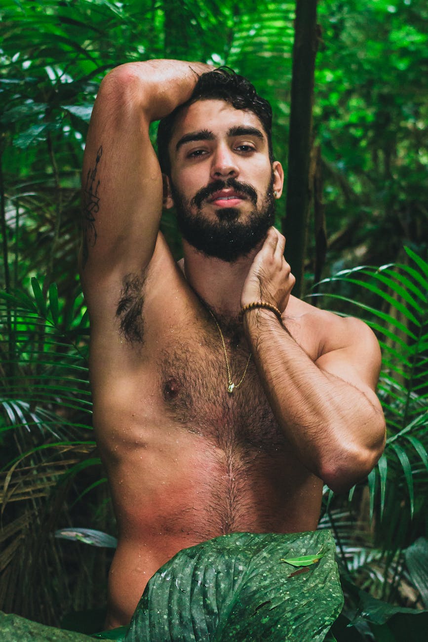 photo of a topless man surrounded by plants