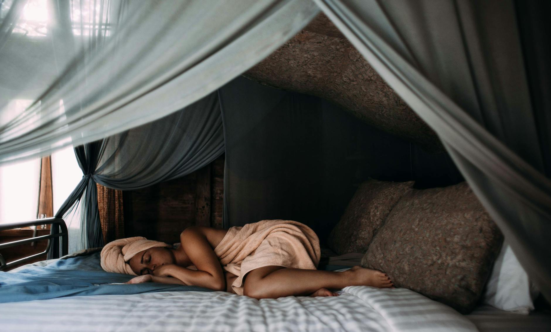 mulher dormindo na cama enrolada em toalha