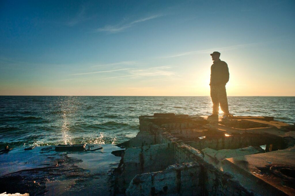 silhouette photo of man standing near the edge of concrete pavement