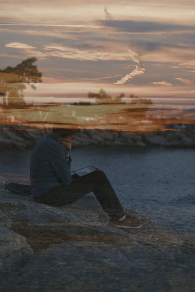 woman sitting on a ground using tablet at dusk