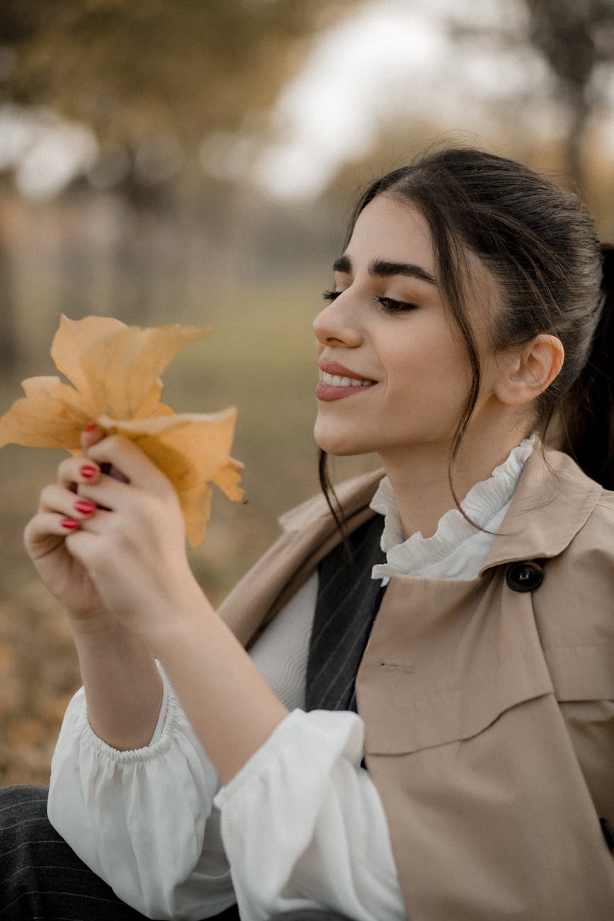 woman looks at autumnal yellow leaves