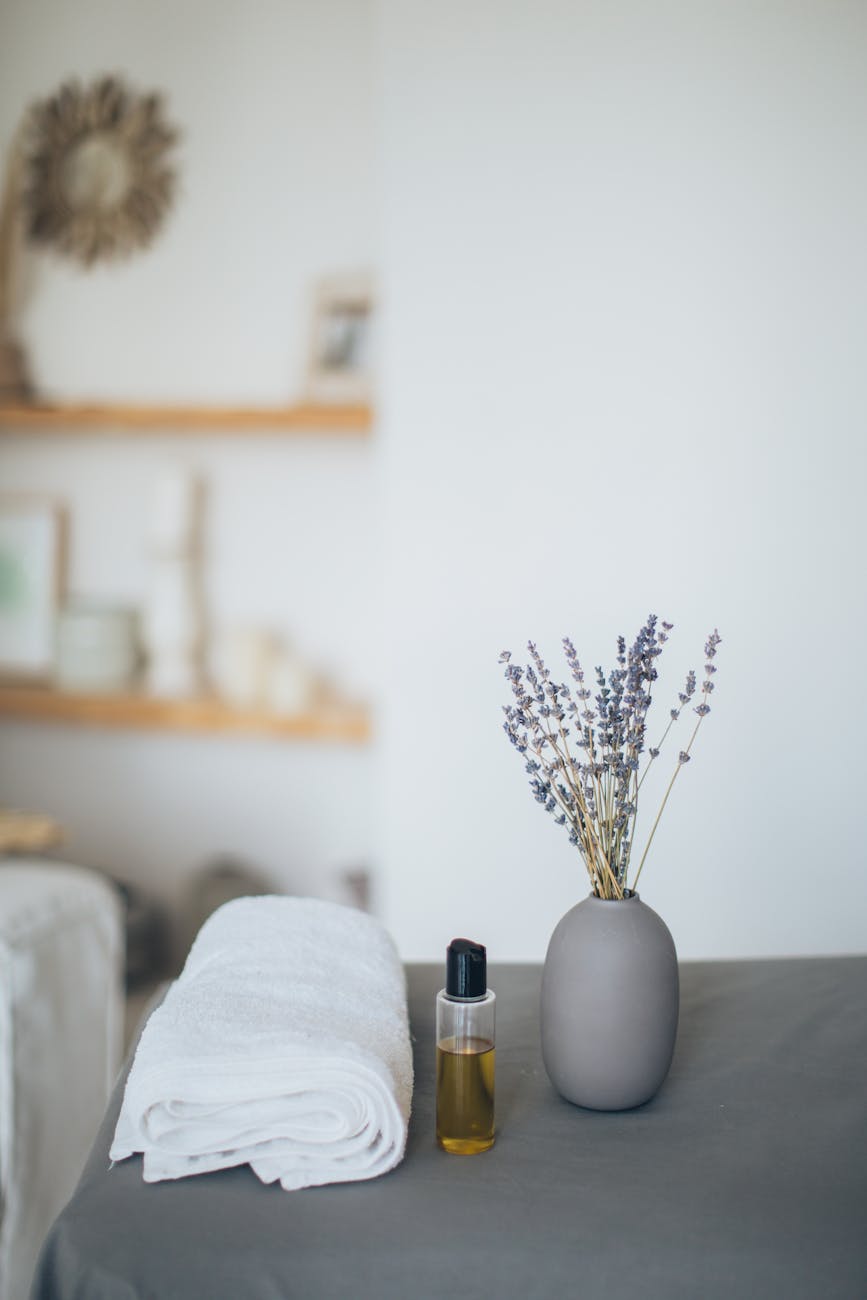 Ramos de lavanda em um poter, óleo de lavanda em um frasco e um toalha